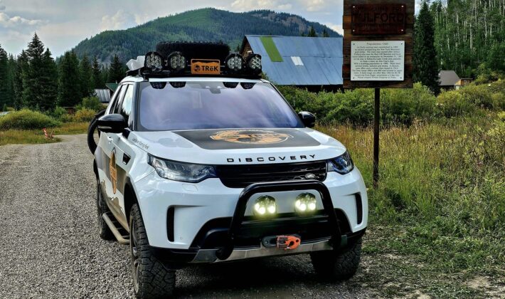 photo of a white Land Rover Discovery 5 in front of some cabins