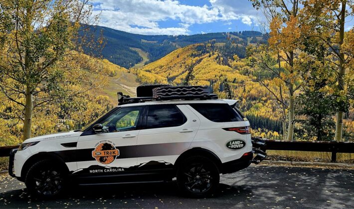 photo of a white Land Rover Discovery 5 in front of a scenic fall landscape