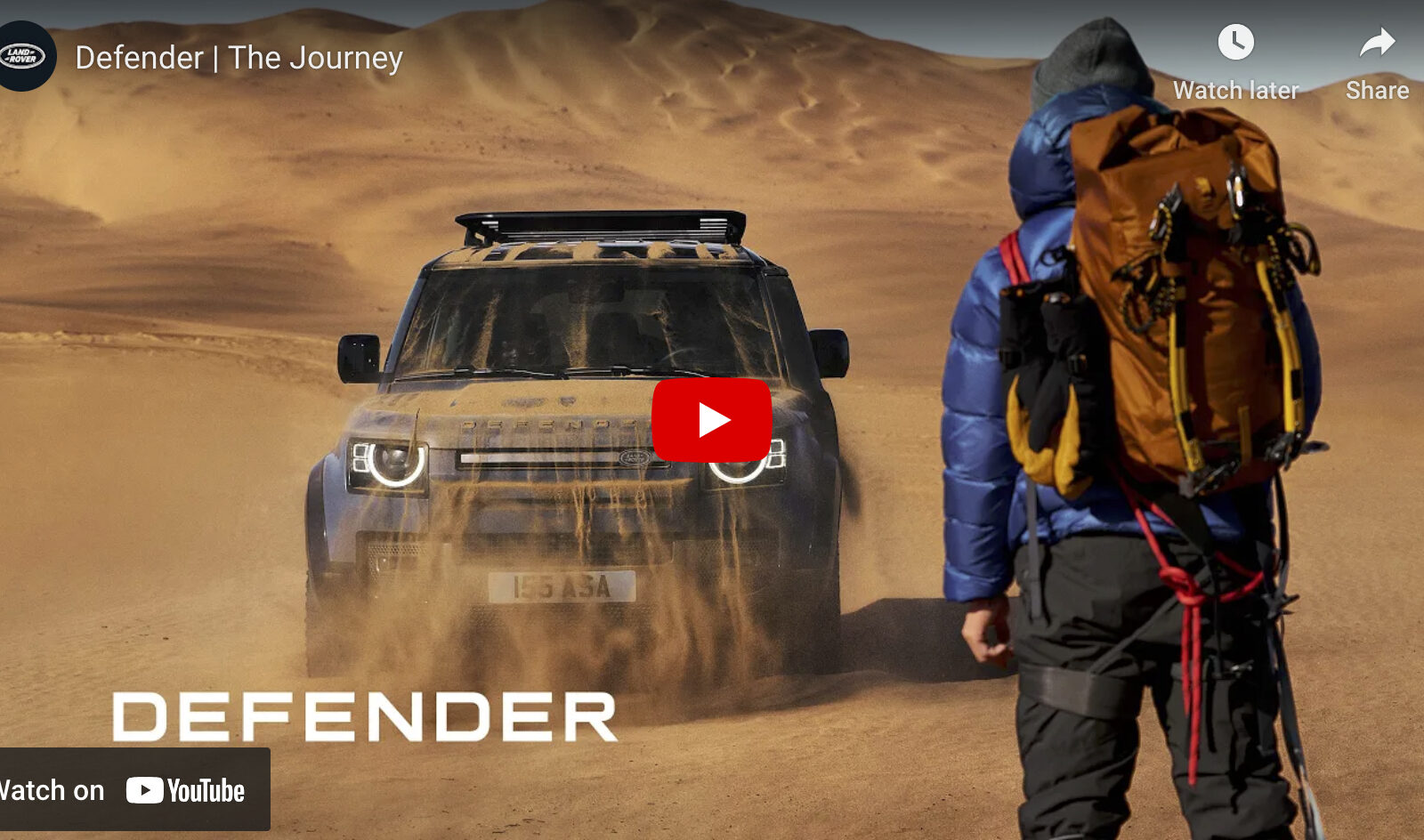 video cover image of a man in mountaineering gear standing in a desert looking at a Land Rover Defender